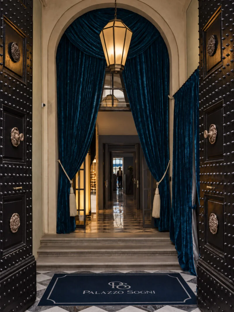 Palazzo Sogni 入口处的拱形门洞、深色木门与蓝色天鹅绒帘